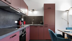 A modern kitchen with dark cabinets, a stainless steel countertop, a coffee maker, and a sink. - Cosy Holiday Apartment "Alpenblick" with Balcony, Terrace & Wi-Fi; Parking Available (Eggstätt)