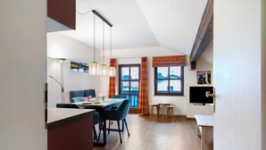 A modern kitchen with a dining area, wooden flooring, and a large window with curtains. - Cosy Holiday Apartment "Alpenblick" with Balcony, Terrace & Wi-Fi; Parking Available (Eggstätt)