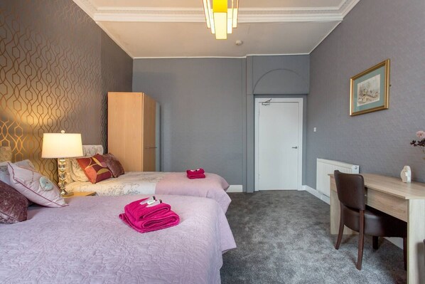 A hotel room with two beds, a desk, and a chair.