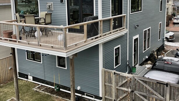 A two-story house with a balcony, a covered patio, and a fenced yard.