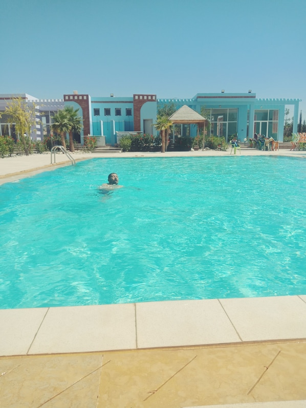 Una piscina al aire libre de temporada, sombrillas, tumbonas