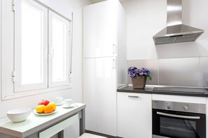 Una cucina moderna con pensili bianchi, una cappa aspirante in acciaio inossidabile e un forno integrato.