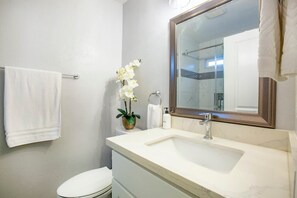 Een badkamer met een wit wastafelmeubel, een spiegel, een toilet en een handdoekrek.