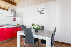 Une cuisine moderne avec un îlot central rouge, des murs blancs et une inscription décorative.