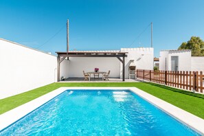 Une piscine rectangulaire dotée d’une terrasse en bois et d’une pergola.