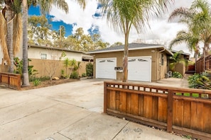 A residential property with a garage, a wooden fence, and a palm tree.