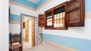 Une chambre à coucher comprenant un lit, une chaise en bois, une armoire et une fenêtre avec des volets en bois.
