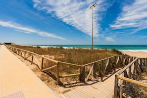Une promenade en bois menant à une plage, avec un ciel dégagé.