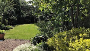 Un jardin bien entretenu, avec une pelouse, divers arbustes et arbres.