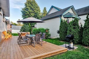 A wooden deck with a table and chairs, a barbecue grill, and a covered patio area. - Retro vibe w/ hot tub, piano lounge and vinyls (Picton)