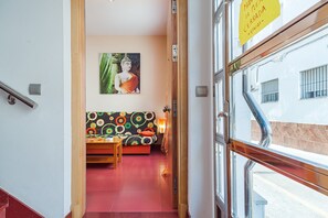 A hallway leading to a room with a Buddha painting, a colorful sofa, and a wooden table.