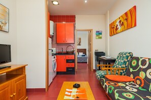 A compact living space with a kitchenette, a sofa, a television, and a dining area.