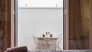 A room with a white brick wall, a table with chairs, and a window with curtains.