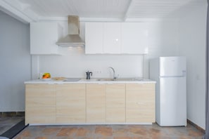Eine moderne Küche mit weißer Arbeitsplatte, Holzschränken, einem Einbauofen und einer Spüle aus Edelstahl.