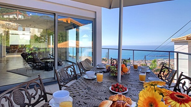 A balcony with a table set for breakfast, overlooking a coastal view. - Villa Moniz - Four Bedroom House, Sleeps 8 (Funchal)
