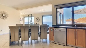 A modern kitchen with a dishwasher, a dining area with six chairs, and a large window offering a view of the outside. - Villa Moniz - Four Bedroom House, Sleeps 8 (Funchal)