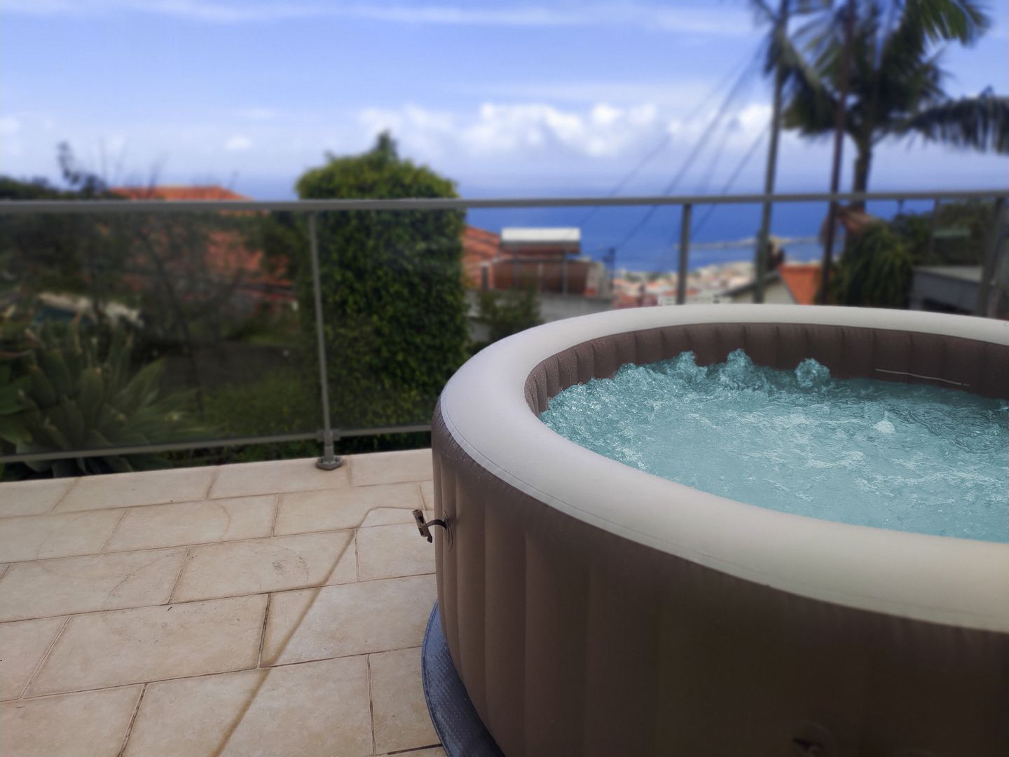 Ein Whirlpool auf einem Balkon mit Blick auf den Ozean und Palmen.