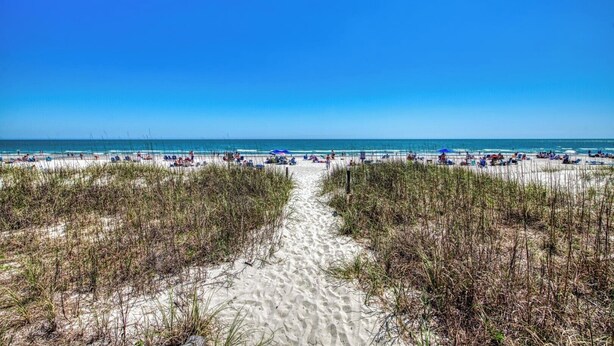A beach with a clear path leading to the water, surrounded by sand and sparse vegetation. - Dreamscaper - Five Bedroom, Four 1/2 Bath Home with private pool (Surfside Beach)