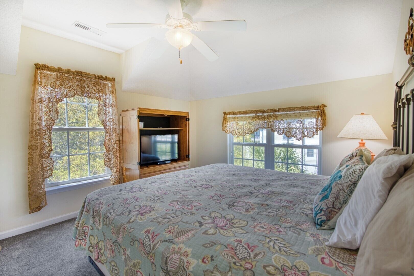 A bedroom with a bed, a TV, and a ceiling fan.