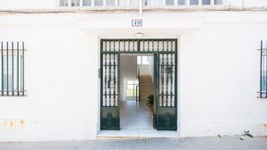 A building entrance with a white facade, a number '49' sign, and a gated entrance.