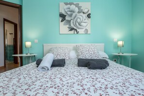 A bed with floral bedding, two bedside tables with lamps, and a large floral painting on the wall. - Central Apartment "El Muellito" On the Beach with Rooftop Terrace & Wi-Fi (El Cotillo)