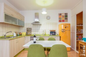 A kitchen with a dining table, chairs, a sink, cabinets, a microwave, a refrigerator, and a clock on the wall. - Central Apartment "El Muellito" On the Beach with Rooftop Terrace & Wi-Fi (El Cotillo)