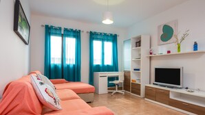 A bedroom with two beds, a desk, a chair, a TV, and a bookshelf.