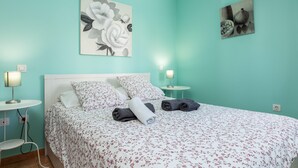 A bed with floral bedding, two bedside tables, and wall art.