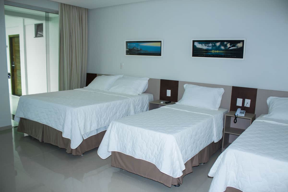 A hotel room with two beds, a nightstand, and a wall-mounted phone.