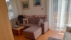 Un salon avec un canapé, une petite table et un tapis. Deux tableaux encadrés sont accrochés au mur.