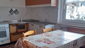 Une cuisine avec une table dressée pour quatre personnes, des chaises en bois, une cuisinière et des placards.