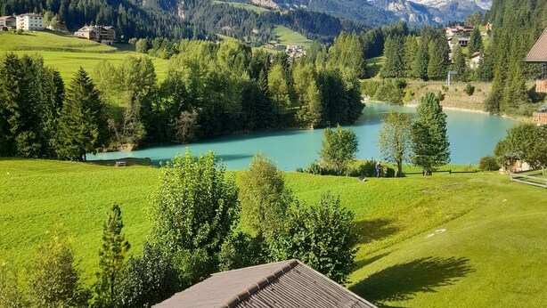 Un paysage de montagne avec un lac, des bâtiments et une structure en bois.