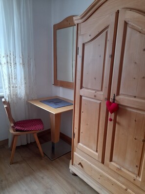 Un bureau en bois avec un miroir, une chaise et une armoire décorée d’un motif en forme de cœur.