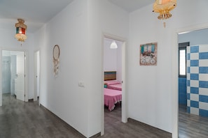 A hallway with a bed, a door, and a wall with a checkered pattern.