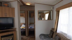 Interiør i en kompakt autocamper med sofa, fjernsyn og et lille bord.
