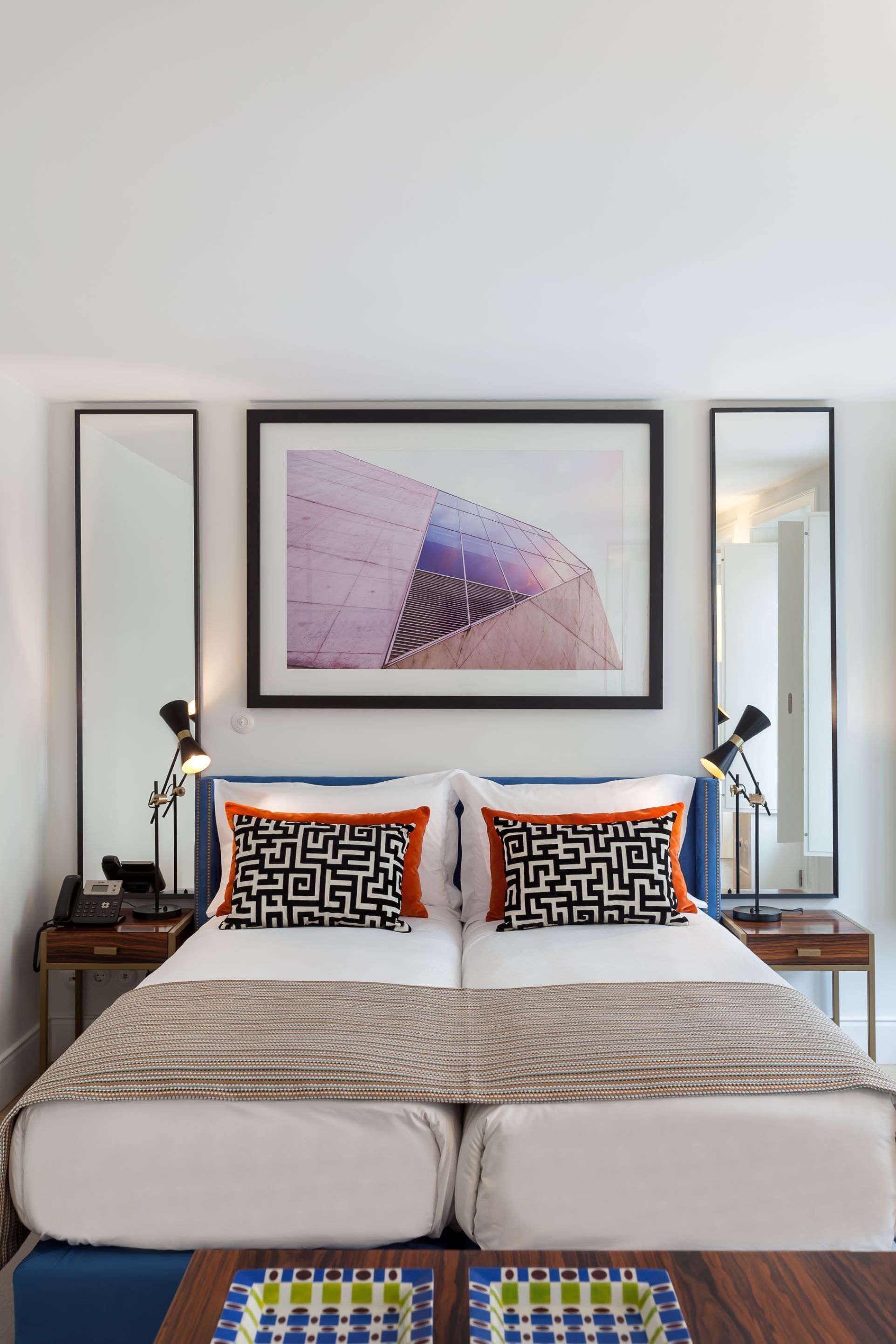 Quarto de hotel com uma cama grande, duas mesas de cabeceira, um quadro na parede e um espelho.