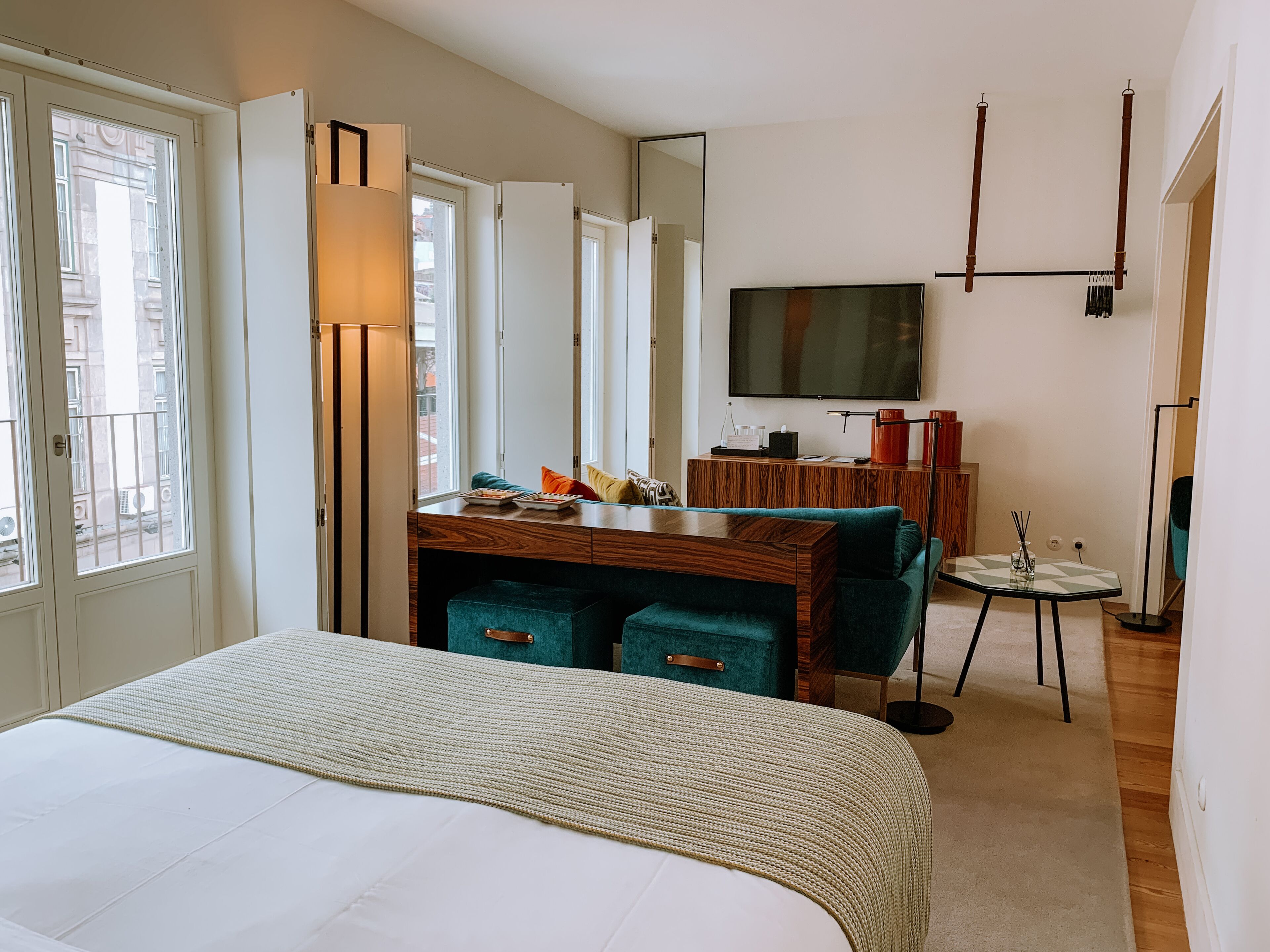 A hotel room with a bed, a desk with a chair, a TV, and a mirror.