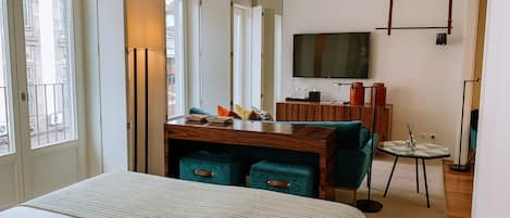 A hotel room with a bed, a desk with a chair, a TV, and a mirror.