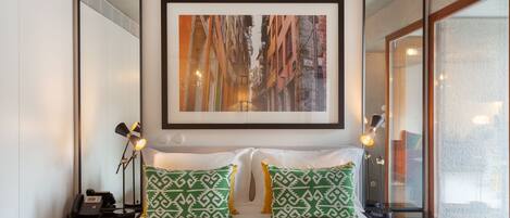 A hotel room with a large bed, two bedside lamps, a telephone, and a framed picture on the wall.