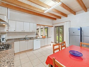 A kitchen with white cabinets, a gas stove, and a red table with chairs.