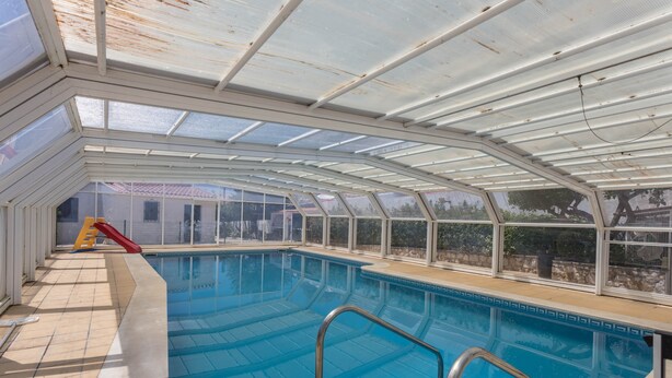 An indoor swimming pool with a glass ceiling, a slide, and a view of the outside. - Spacious Villa "Morena" with Wi-Fi, Garden, Terrace, Balcony & Pool (Albufeira)