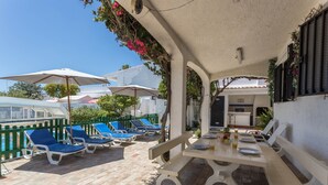 A covered outdoor area with a table set for dining, lounge chairs, and umbrellas. - Spacious Villa "Morena" with Wi-Fi, Garden, Terrace, Balcony & Pool (Albufeira)