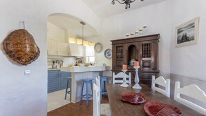 A kitchen with a central island, white bar stools, a wooden dining table, and a chandelier. - Spacious Villa "Morena" with Wi-Fi, Garden, Terrace, Balcony & Pool (Albufeira)