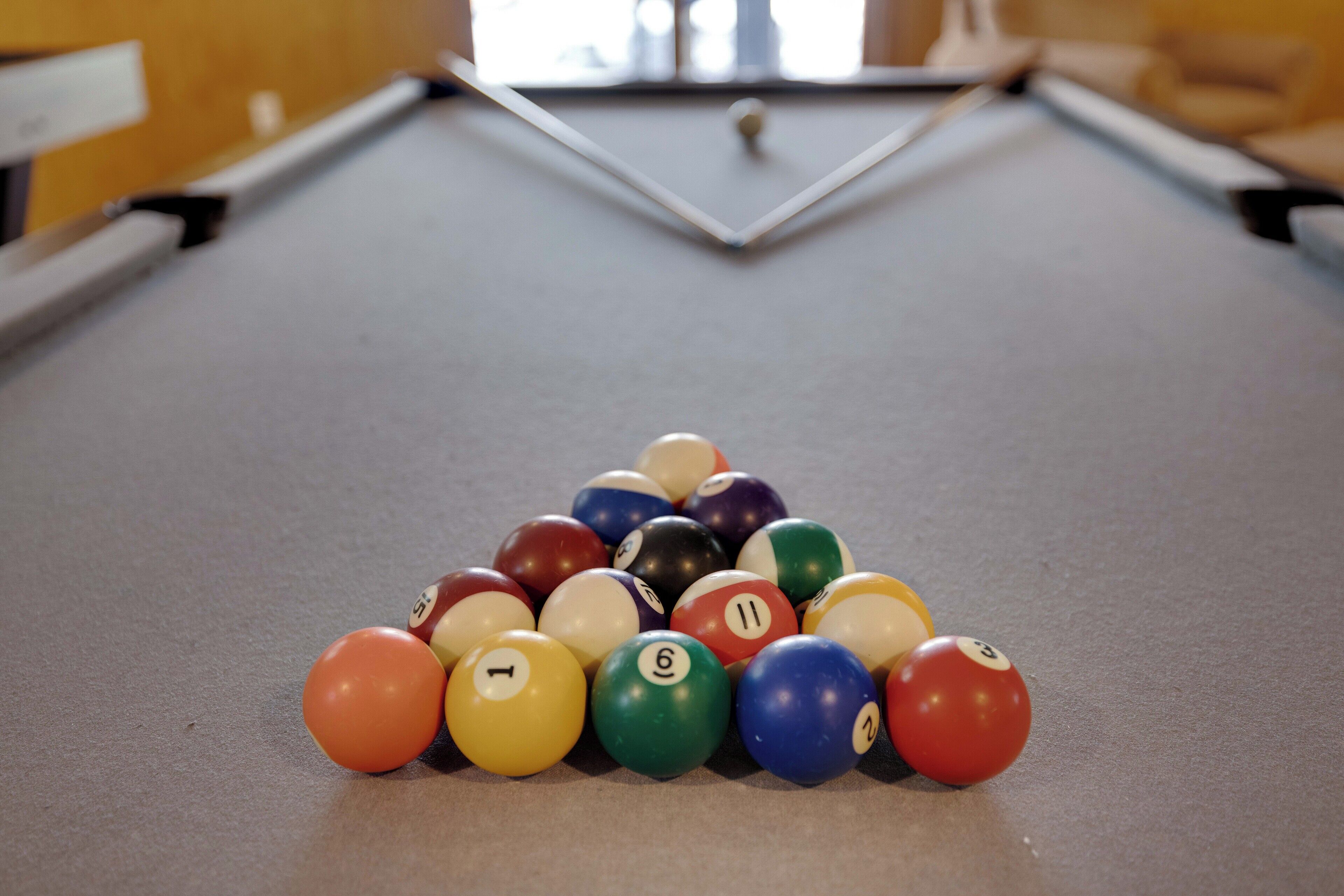 A pool table with a triangular arrangement of billiard balls.