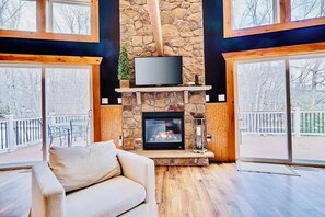 Una sala de estar acogedora con chimenea de piedra, televisor de pantalla plana y un sofá confortable.