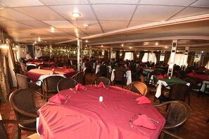 A dining area with round tables covered in red tablecloths, arranged in rows with chairs. - Diamond ship Hotel (Cairo)