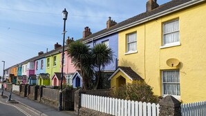 A row of colorful terraced houses with a white picket fence and a lamp post. - 2-bedroom sea view property 1 min from the sea & SW Coast Path (Bideford)