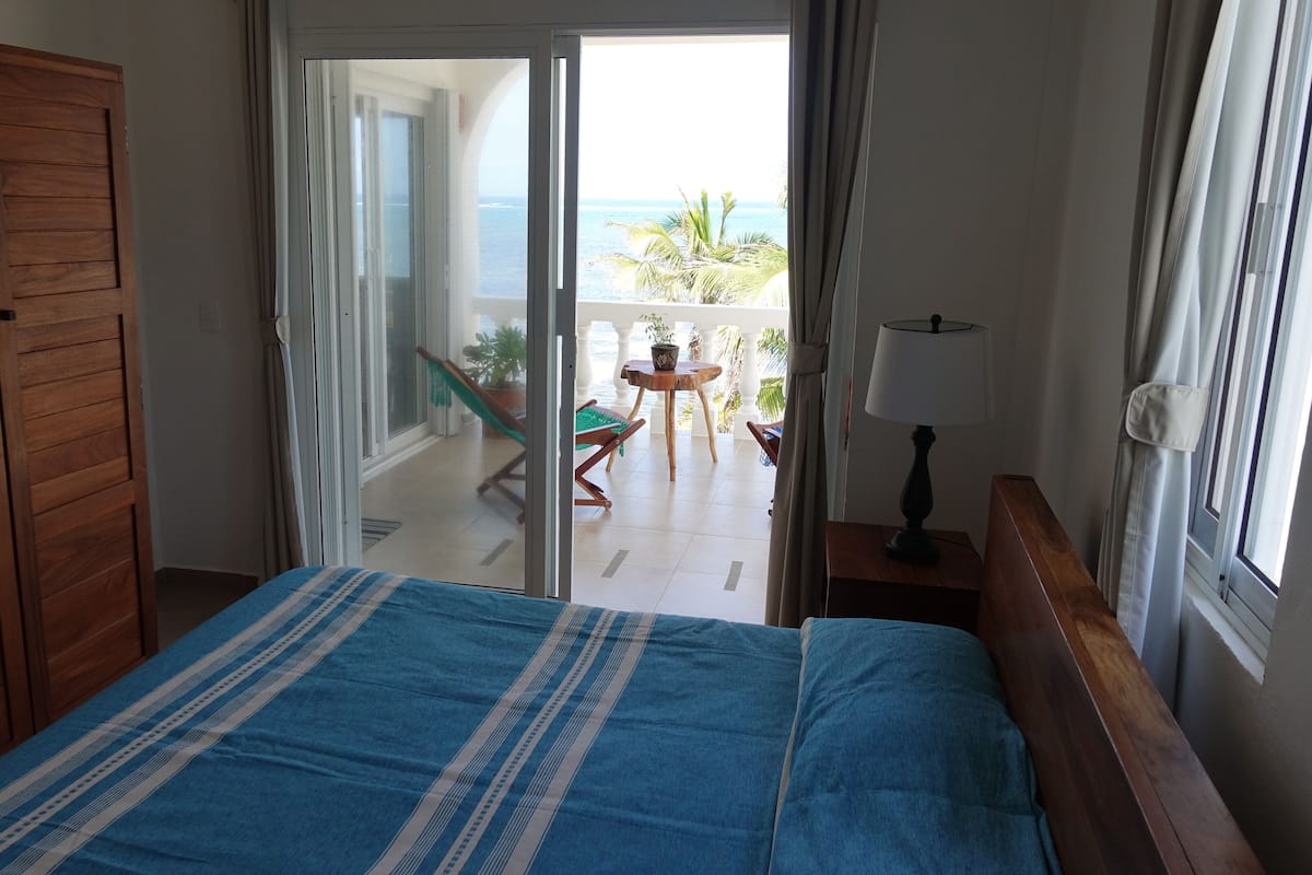 Ein Schlafzimmer mit Bett, Holzschrank und einem Balkon mit Meerblick.