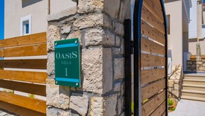 Un muro de piedra con un letrero que dice "Oasis Villa I".