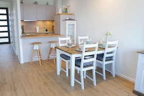 A modern kitchen with a wooden island, white cabinets, and bar stools. - Apartment "Strandmupfel" with sea view, contactless check-in (Sierksdorf)